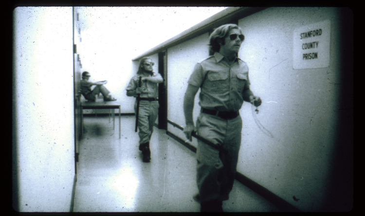 A photo from the 1971 Stanford Prison Experiment showing a guard and prisoner.